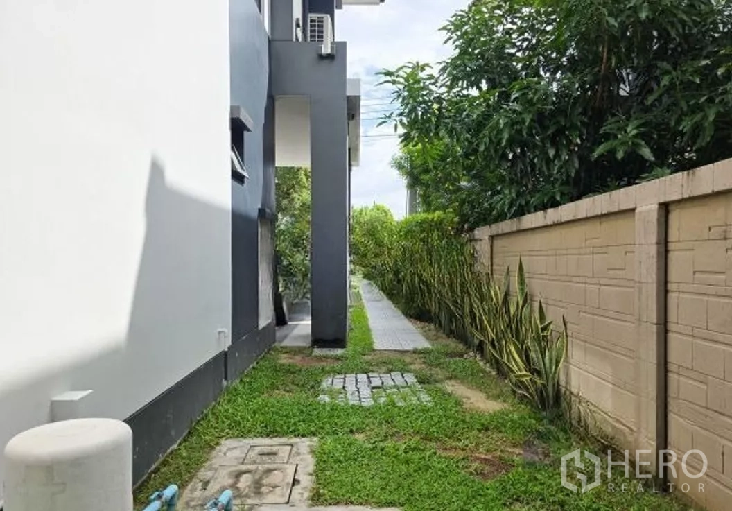 Detached House for sale in Bang Kapi, Bangkok - Side yard beside the house with grass strip and paved walkway.
