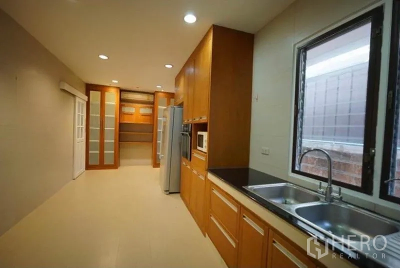 独立式住宅 出租在Bang Phli, Samut Prakan - 厨房另一角，双槽水池、储物柜与大窗户。