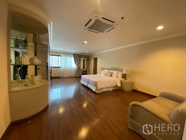 Condominium for rent in Watthana, Bangkok - Large master bedroom with king bed, wood floors, ceiling cassette AC and curved display shelves.