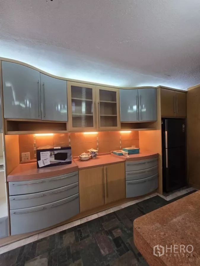 Condominium for rent in Pathum Wan, Bangkok - Kitchen cabinetry with under-cabinet lighting and full-size refrigerator.