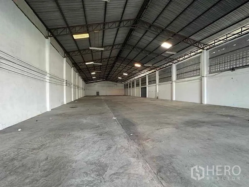 Warehouse for rent in Mueang Samut Sakhon, Samut Sakhon - Wide-span warehouse interior with high steel truss roof, bright strip lighting and smooth concrete floor.