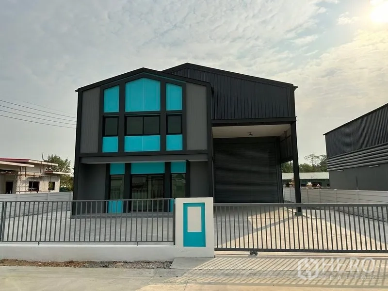 工厂 出租或出售在Bang Bua Thong, Nonthaburi - 带青色点缀两层办公室与宽大卷闸门的现代小型工厂正面。