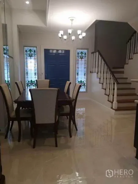 Detached House for rent in Wang Thonglang, Bangkok - Formal dining room with chandelier, blue front door, and white staircase with wood steps.