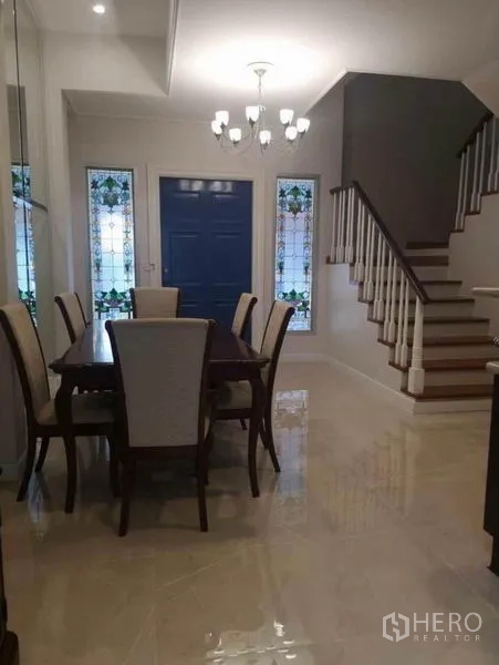 Detached House for rent in Wang Thonglang, Bangkok - Formal dining room with chandelier, blue front door, and white staircase with wood steps.