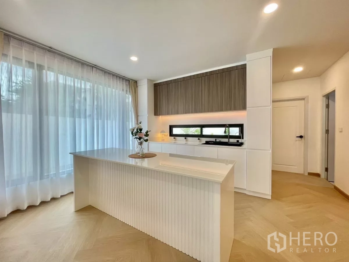 独立式住宅 出售在Prawet, Bangkok - 现代厨房，白色中岛、木柜、长条窗和灯带。