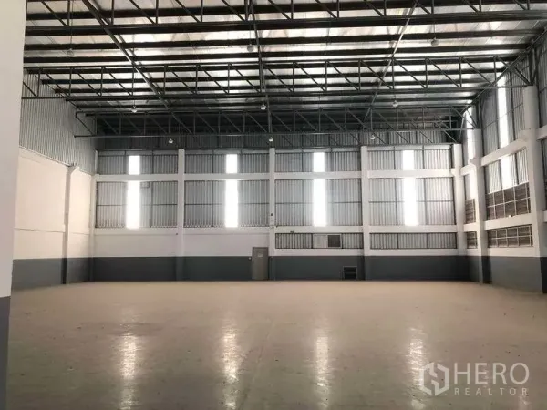 Factory for rent or sale in Samut Prakan - Spacious warehouse hall with high steel roof, skylight panels and clear open floor space.