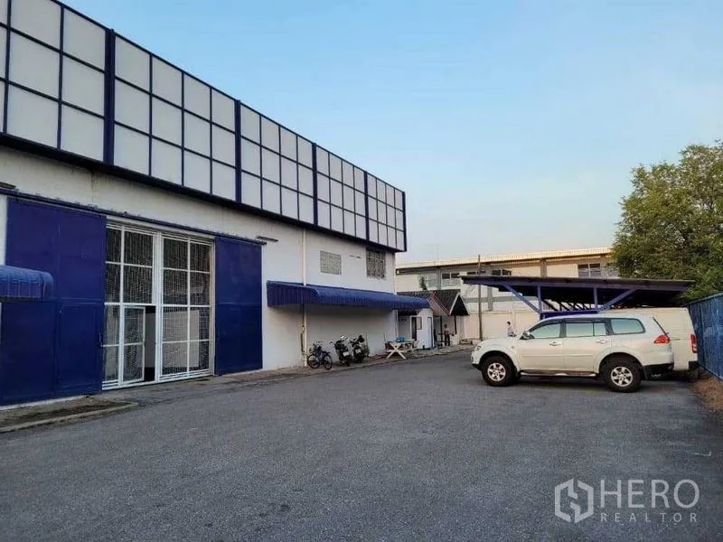 Warehouse for rent in Phra Khanong, Bangkok - Warehouse exterior with wide driveway, blue facade and on-site parking