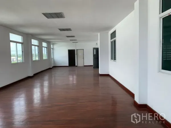 Warehouse for rent in Lam Luk Ka, Pathum Thani - Bright second-floor office space with wood flooring, white walls and rows of windows.
