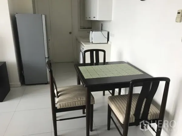 Condominium for rent in Bang Rak, Bangkok - Compact dining nook for four beside a pantry kitchen with refrigerator, microwave and washer.