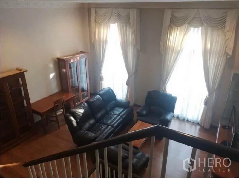 Detached House for rent in Wang Thonglang, Bangkok - Double-height lounge with large curtained windows, wooden flooring, and leather seating.