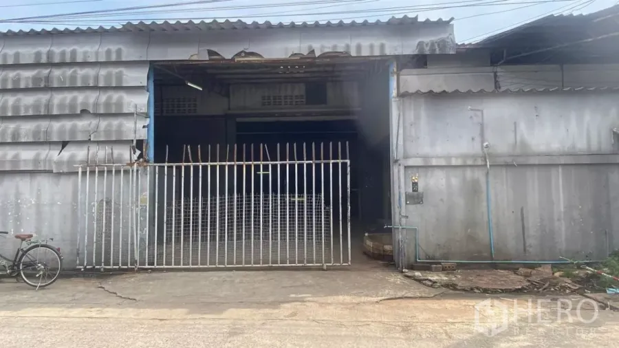 Factory for rent in Bang Sao Thong, Samut Prakan - Metal-clad factory frontage with wide sliding gate and vehicle access in an industrial area.