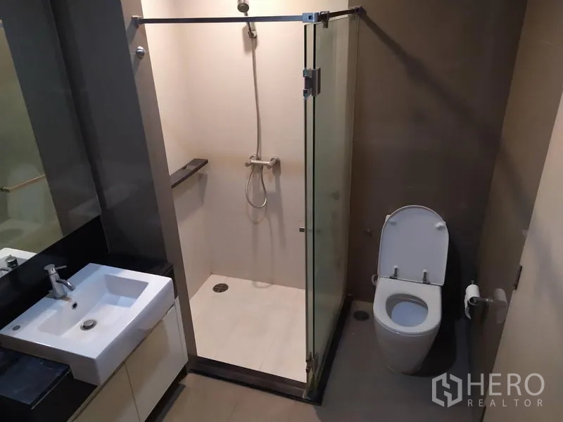 Condominium for sale in Khlong Toei, Bangkok - Bathroom featuring a glass-enclosed shower, vanity and toilet.