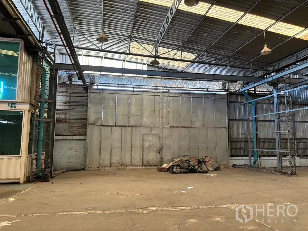 โรงงาน for rent or sale in Bang Sao Thong, Samut Prakan - ภายในโรงงานมีเครื่องจักรและรถแทรกเตอร์ใต้หลังคาโครงเหล็ก.