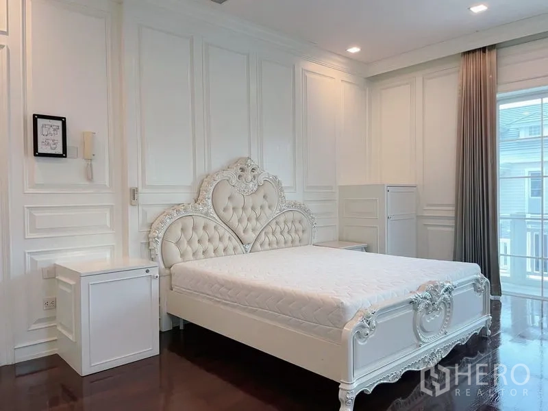 Detached House for rent or sale in Bang Phli, Samut Prakan - Master bedroom with ornate white bed, paneled walls, wood floors, and balcony access.