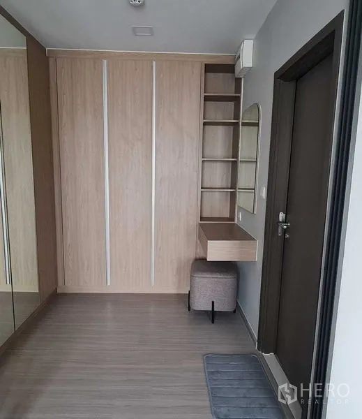 Condominium for rent in Phra Khanong, Bangkok - Bedroom corner with built-in wardrobe, mirror, open shelves, and a stool.