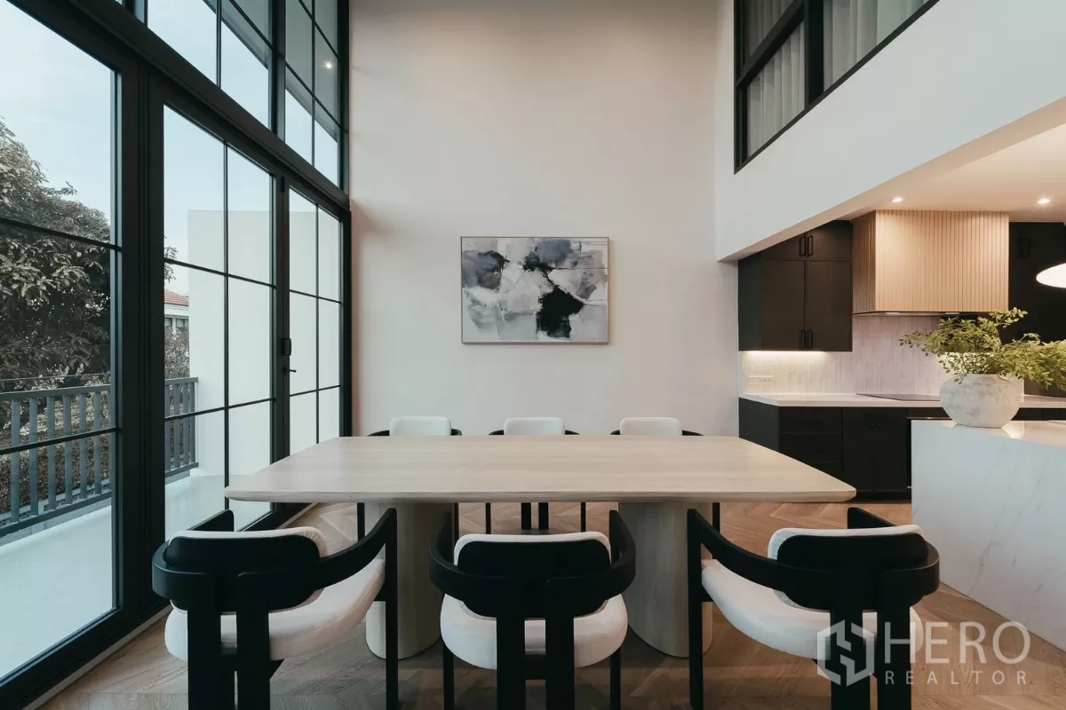 联排别墅 出租在Watthana, Bangkok - 明亮餐区，高挑黑框落地窗与八人餐桌。