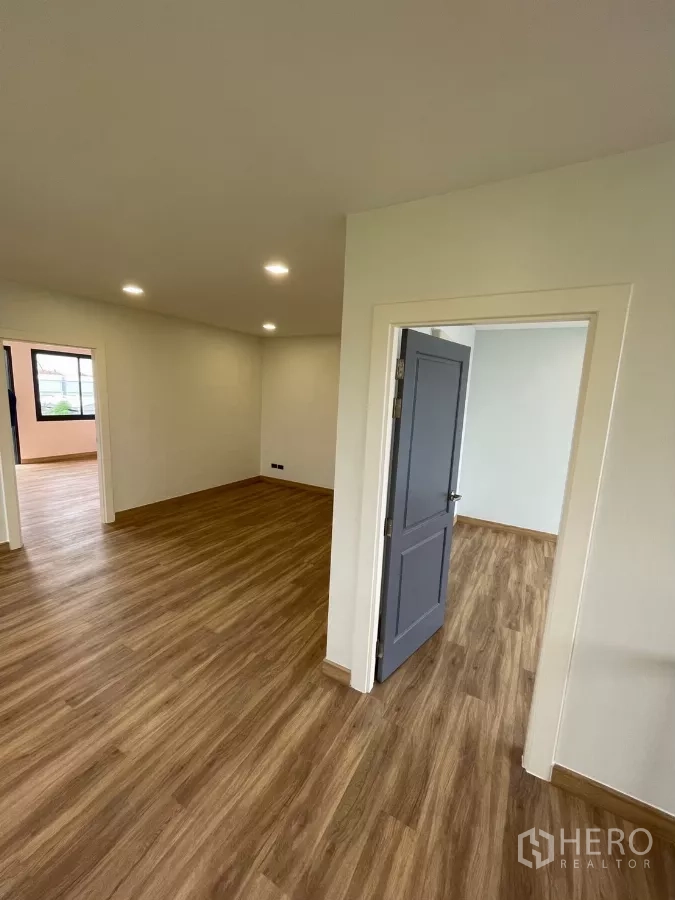 Home Office for rent in Khan Na Yao, Bangkok - Hallway connecting rooms with wood floors and a gray interior door.
