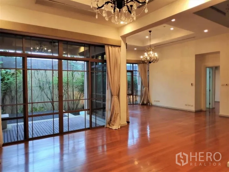 独立式住宅 出租在Watthana, Bangkok - 开放式客餐厅，推拉落地门连接木平台与庭院。