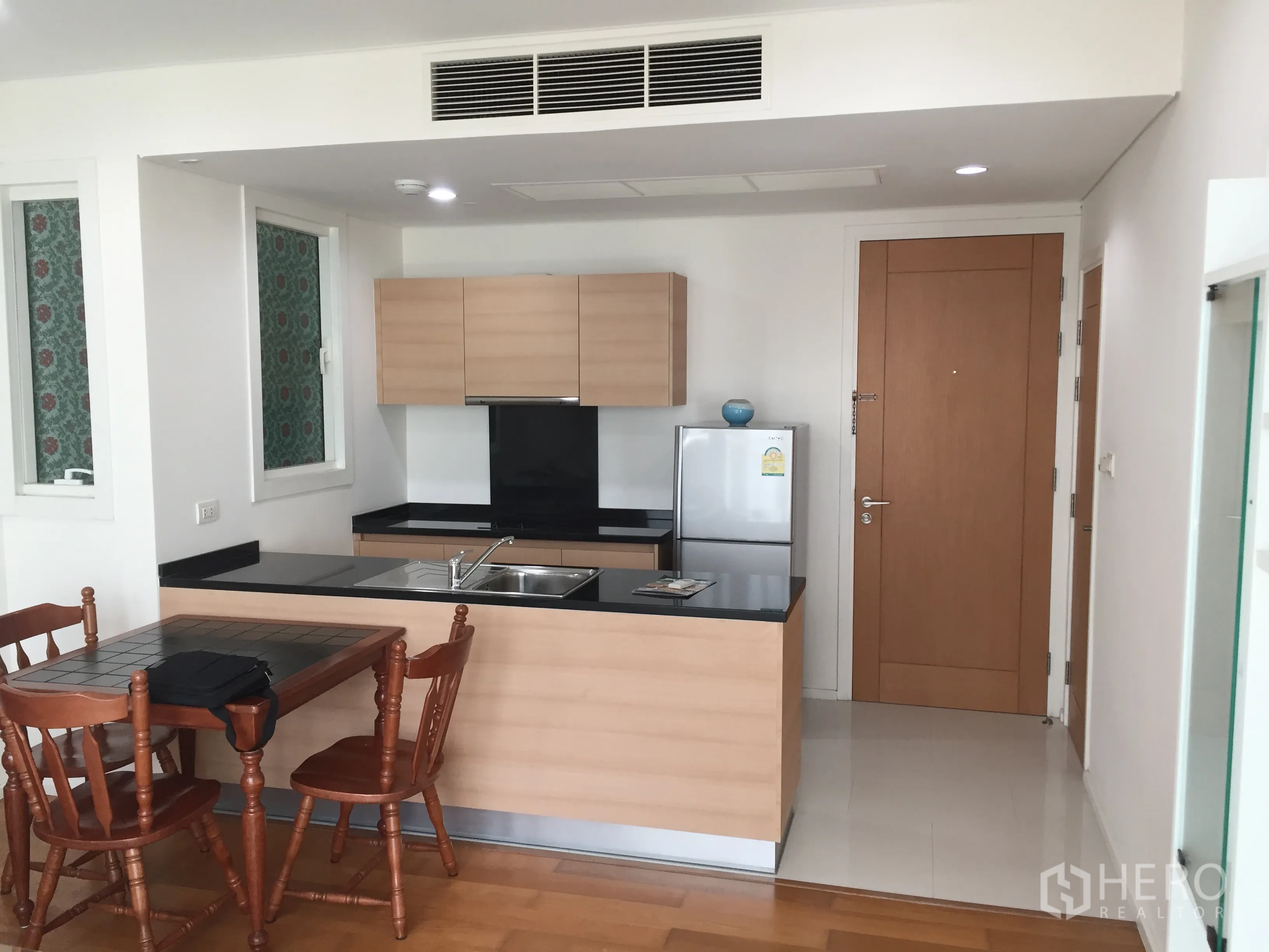 คอนโด ให้เช่าหรือขายในWatthana, Bangkok - ครัวเปิดตู้ลายไม้ เคาน์เตอร์หินสีดำ พร้อมโต๊ะรับประทานอาหาร