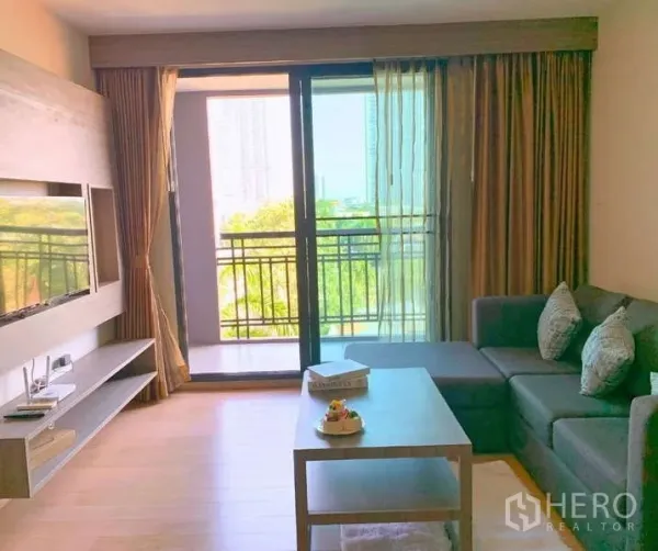 Condominium for rent - Living area opening to a balcony through sliding glass doors with leafy views.