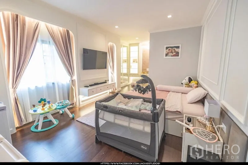 Detached House for sale in Pak Kret, Nonthaburi - Light‑filled kids’ bedroom with crib, TV console and soft curtains.