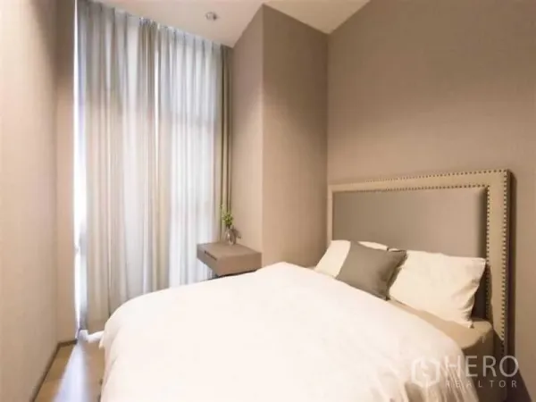 Condominium for rent in Bang Rak, Bangkok - Second bedroom with tall window, soft drapes, bedside ledge and neutral bedding.