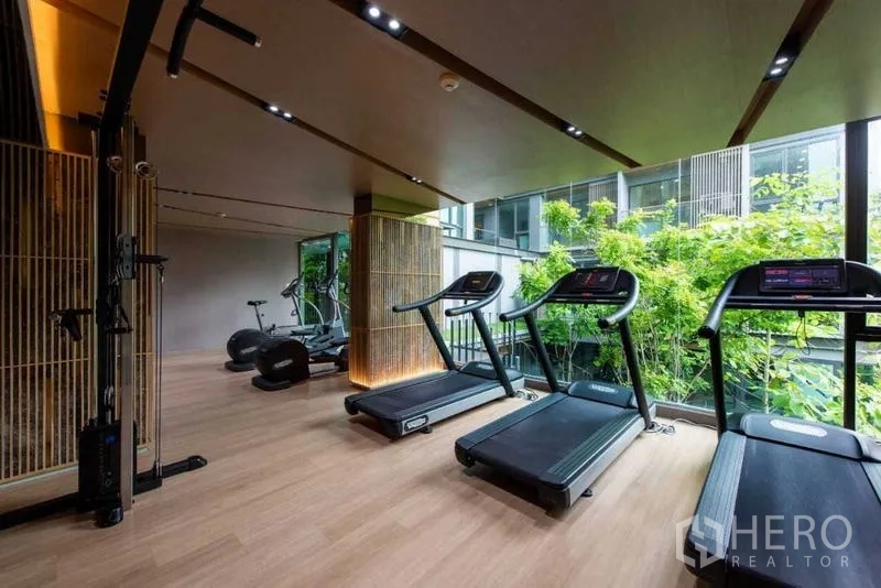 Condominium for rent in Huai Khwang, Bangkok - Modern condominium fitness room with treadmills facing garden views.