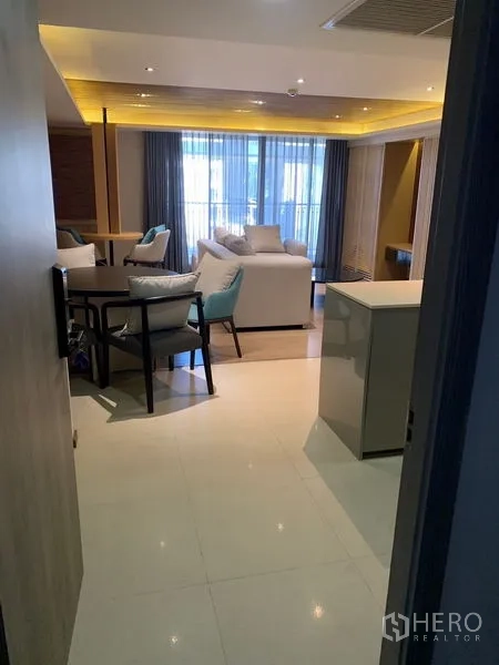 คอนโด ให้เช่าในPathum Wan, Bangkok - พื้นที่นั่งเล่นและรับประทานอาหารแบบเปิดโล่ง โซฟา L พร้อมหน้าต่างสูงจรดเพดานและม่านโปร่ง