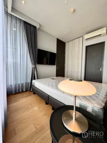 คอนโด ให้เช่าหรือขาย - ห้องนอนสว่างด้วยหน้าต่างบานใหญ่ ทีวีติดผนัง แอร์ และพื้นไม้