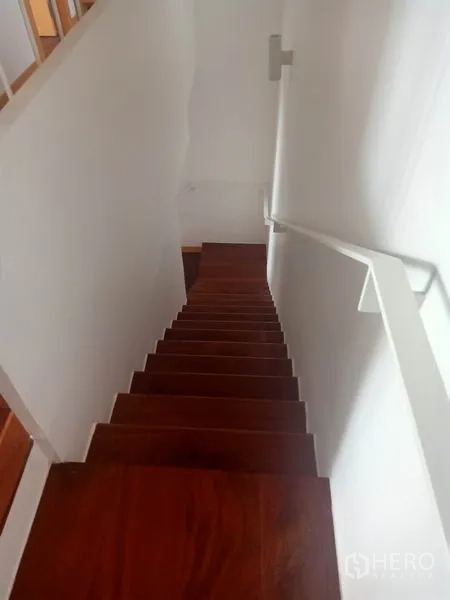 Condominium for rent in Watthana, Bangkok - Interior staircase with polished wooden steps and a white handrail in a multi-level layout.