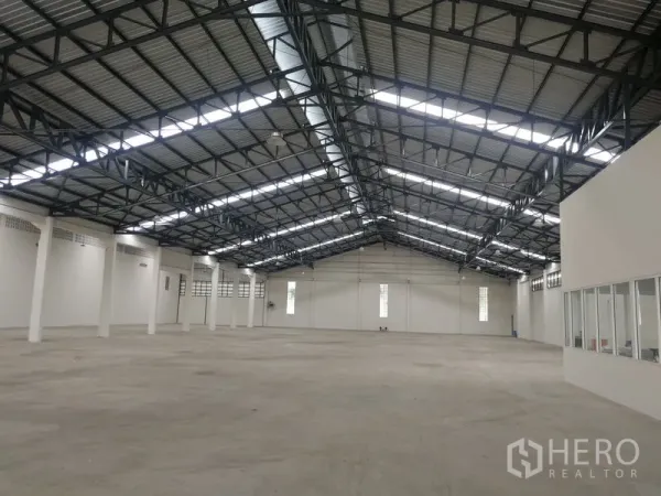 Warehouse for rent in Phra Pradaeng, Samut Prakan - Clear‑span storage hall with high ceilings, skylight strips and white perimeter walls for efficient racking.