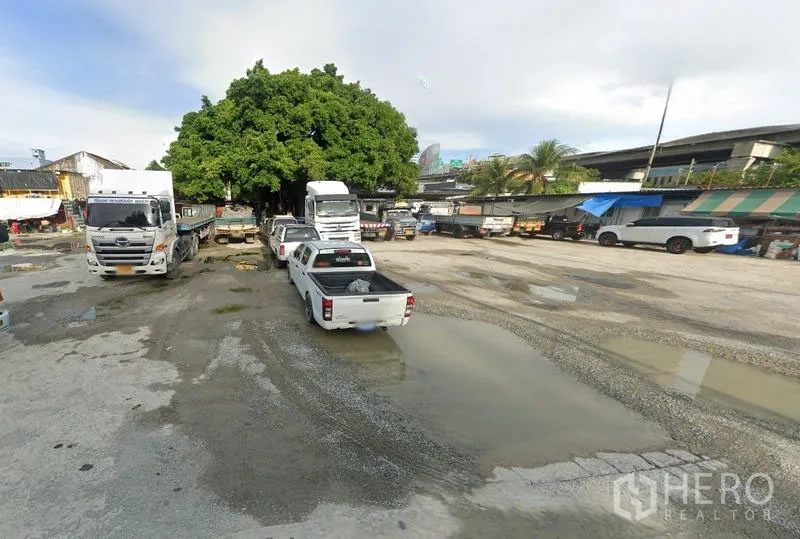 ที่ดิน ให้เช่าในBang Na, Bangkok - ลานหินคลุกเปิดโล่งในย่านบางนา ใช้จอดรถบรรทุกและกระบะ มีต้นไม้ใหญ่และเพิงร้านด้านข้าง