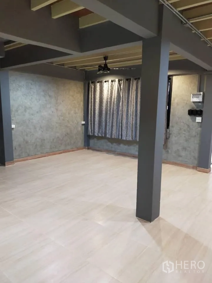 Detached House for rent in Watthana, Bangkok - Open-plan room with central column, tiled flooring, ceiling lights and curtained windows.