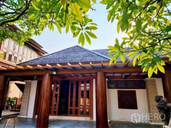 Detached House for sale in Bueng Kum, Bangkok - Tropical-style house facade with timber columns, gabled roof and lush greenery.