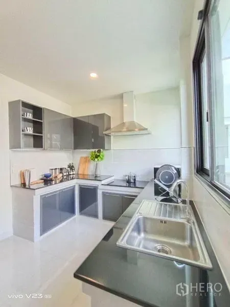 Detached House for sale in Wang Thonglang, Bangkok - Bright L-shaped kitchen with window, stainless sink, range hood and glossy cabinets.