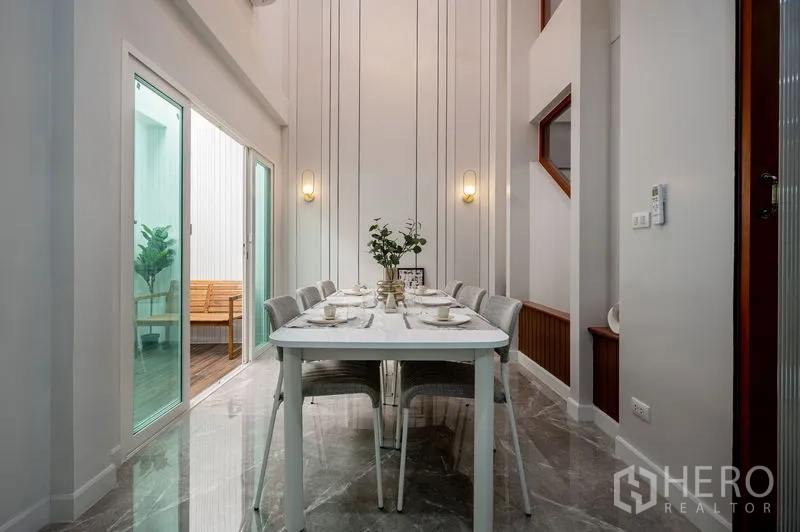 Townhouse for sale in Din Daeng, Bangkok - Double-height dining room with wall sconces and modern decor.