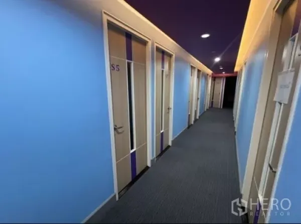 零售空间 出租在Bang Rak, Bangkok - 明亮走廊，蓝色墙面与编号房门通向多个私密房间的零售单位。