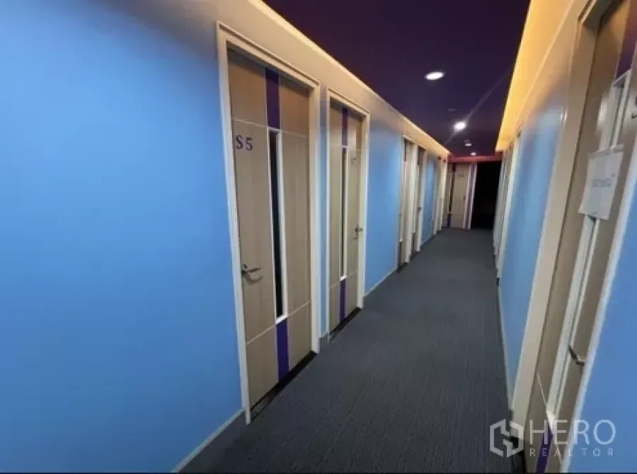 零售空间 出租在Bang Rak, Bangkok - 明亮走廊，蓝色墙面与编号房门通向多个私密房间的零售单位。