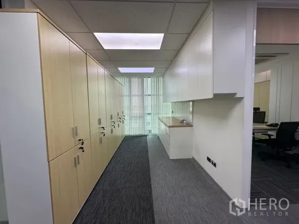 Office Space for rent - Storage corridor featuring full-height built-in cabinets, counter space, and vertical blinds filtering daylight.