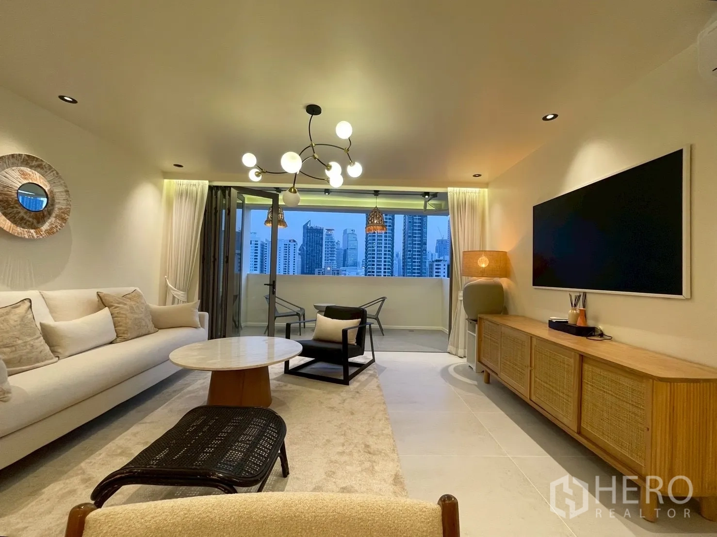 Condominium for sale in Watthana, Bangkok - Elegant living room with sofa, media wall, and city views.
