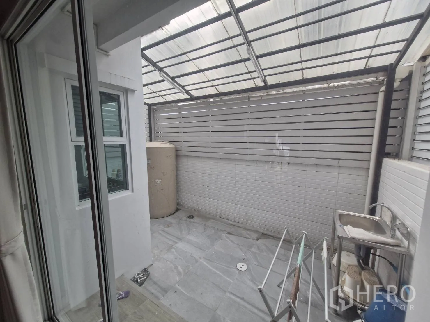 Townhouse for sale in Rat Burana, Bangkok - Covered utility terrace with translucent roof, sink, and privacy fence.