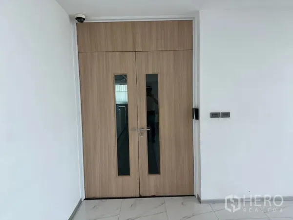 Office Space for rent - Secure wooden double entry doors with narrow glass panels and CCTV in a modern office corridor.
