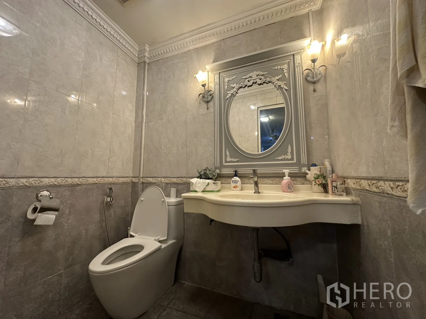 Shophouse for sale in Watthana, Bangkok - Classic tiled bathroom with wall sconces, framed mirror and toilet.