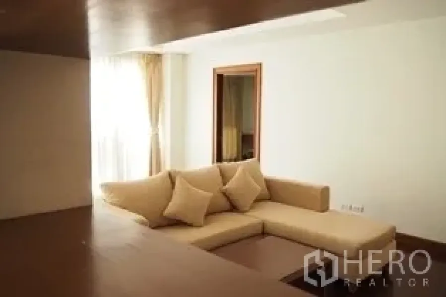 Condominium for rent in Pathum Wan, Bangkok - Bright living room with beige sectional sofa, recessed ceiling and wood floors.