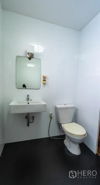 Townhouse for rent in Khlong Toei, Bangkok - Simple guest restroom with white walls, pedestal sink and toilet.