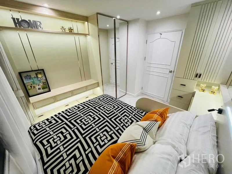 Condominium for sale in Yan Nawa, Bangkok - Bedroom with orange accent pillows, bedside vanity, and sleek built-ins.