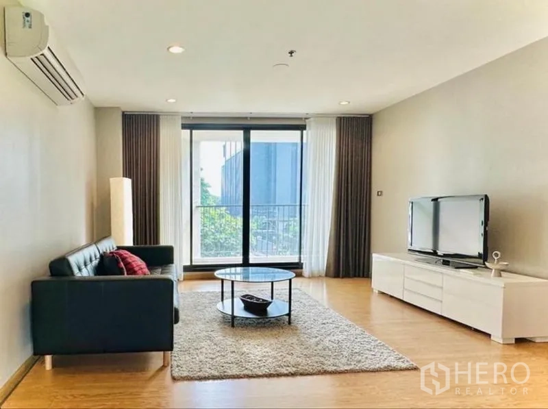 Condominium for rent in Watthana, Bangkok - Spacious living room with sofa, TV unit and sliding doors to the balcony.