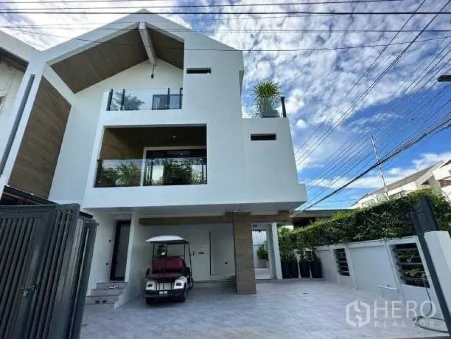 Detached House for rent in Suan Luang, Bangkok - Modern three-storey detached house facade with balconies and driveway.