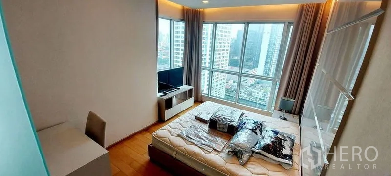 Condominium for rent in Ratchathewi, Bangkok - Bright master bedroom with floor-to-ceiling windows and Bangkok skyline view.