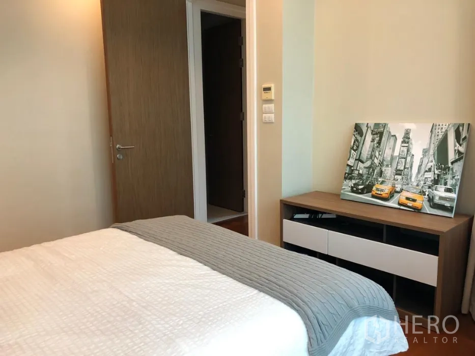 公寓 出租或出售在Khlong Toei, Bangkok - 卧室朝门方向视角，带矮柜与城市装饰画。